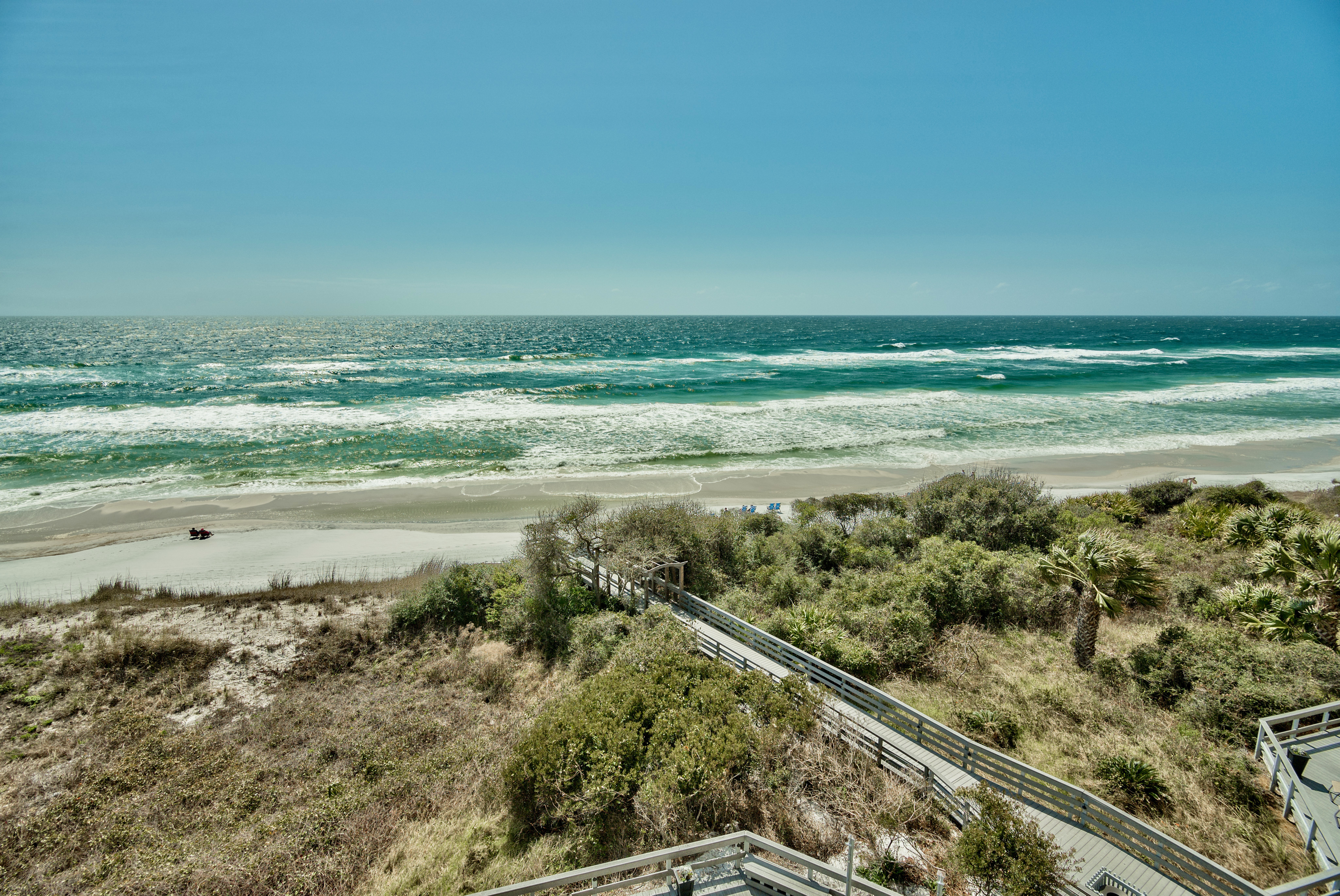 The boardwalk to the beach surrounded by native vegetation at One Seagrove Place with the gulf in the background